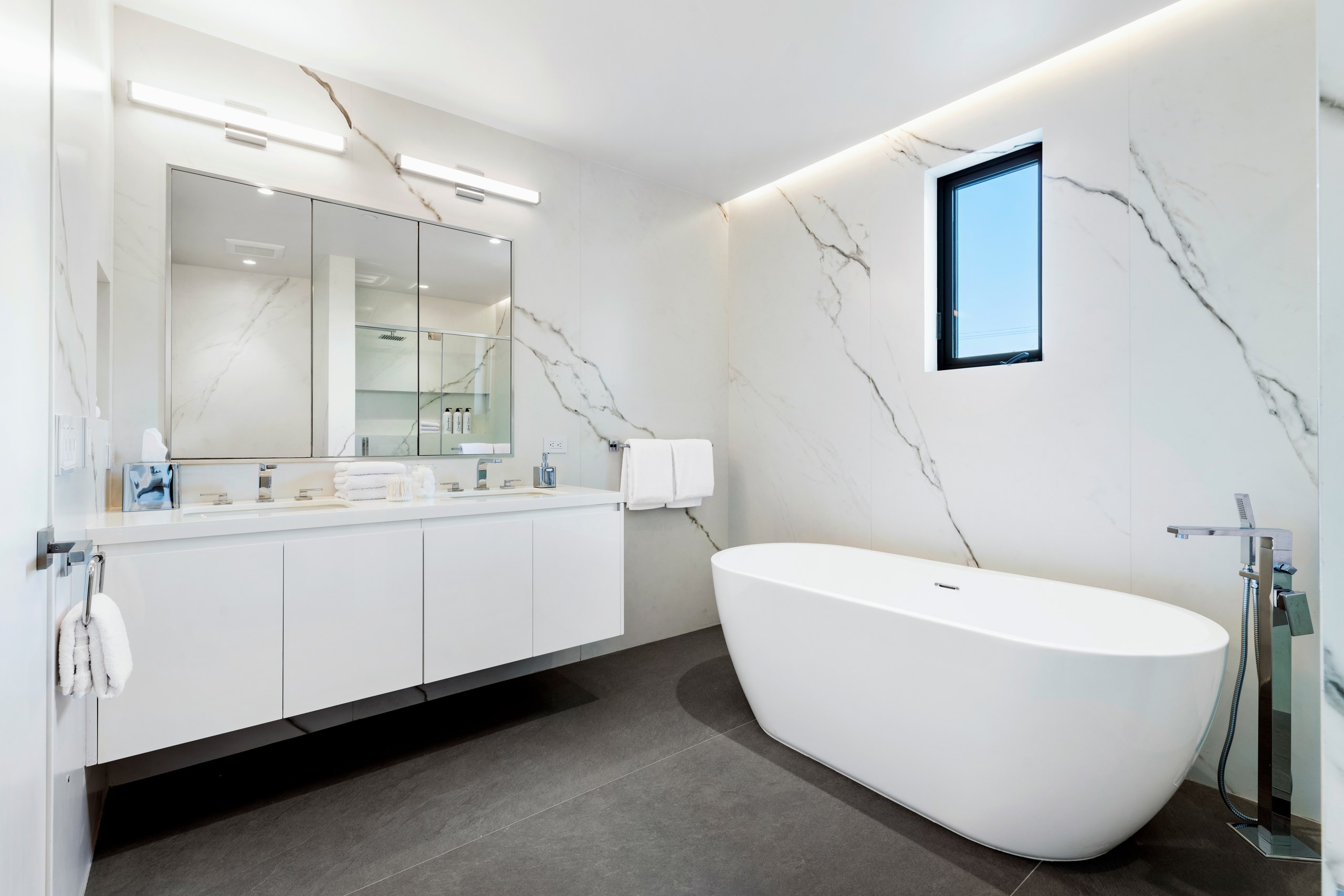Marble-clad primary bath with freestanding tub at Lumiere at Malcolm